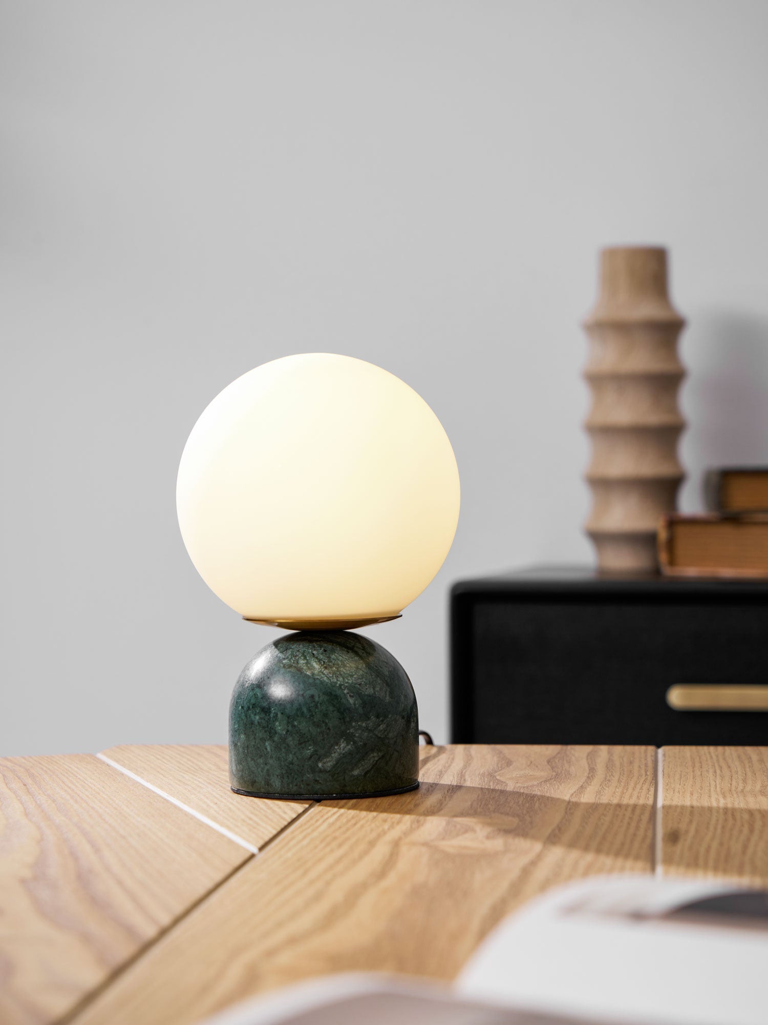 Marble table lamp with glowing orb beside a vase of flowers