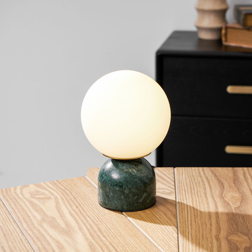 Sylas table lamp lit warmly on a wooden nightstand