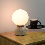 Marble base lamp with white glass orb on a console table
