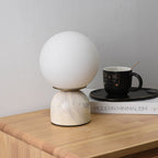Glass orb table lamp casting warm light in a styled room
