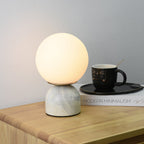 Sylas table lamp glowing softly beside a stack of books