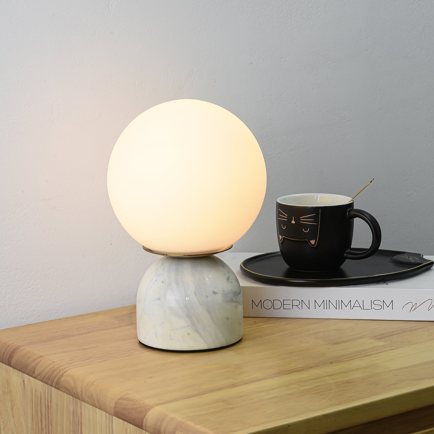 Sylas table lamp glowing softly beside a stack of books