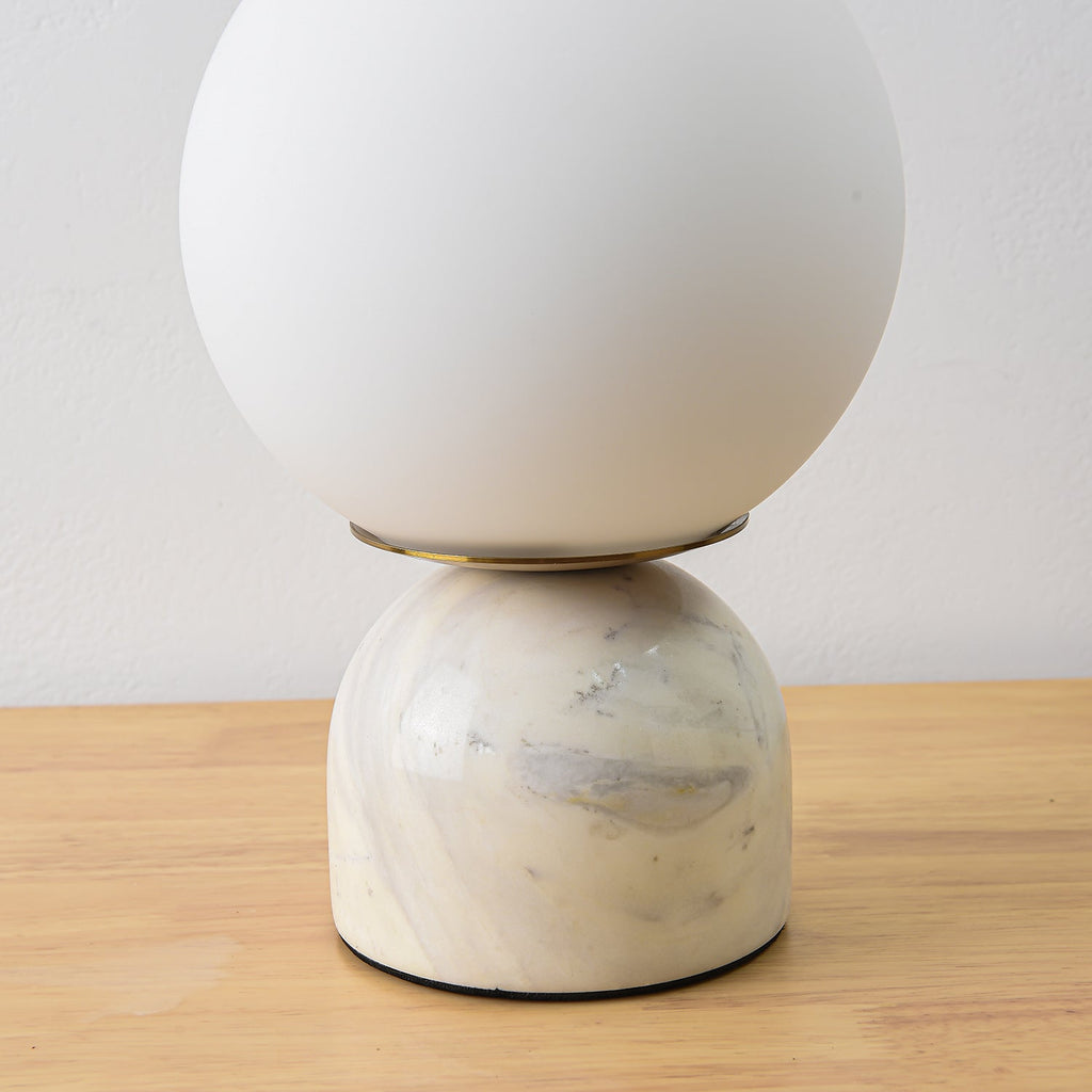 White glass globe lamp with marble base in a cosy interior