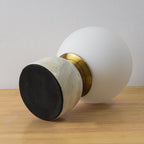 Marble table lamp with glowing orb beside a neutral sofa