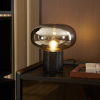 Another angle of the lit Clérachic table lamp on the same dark cabinet, the glass dome reflecting the room's warm light.