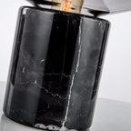 An extreme close-up of the Clérachic table lamp's black marble base, showing its natural veining beneath the glass dome.