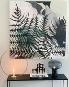 The Clérachic table lamp on a narrow console table beside a lit candle sconce and a framed fern print.