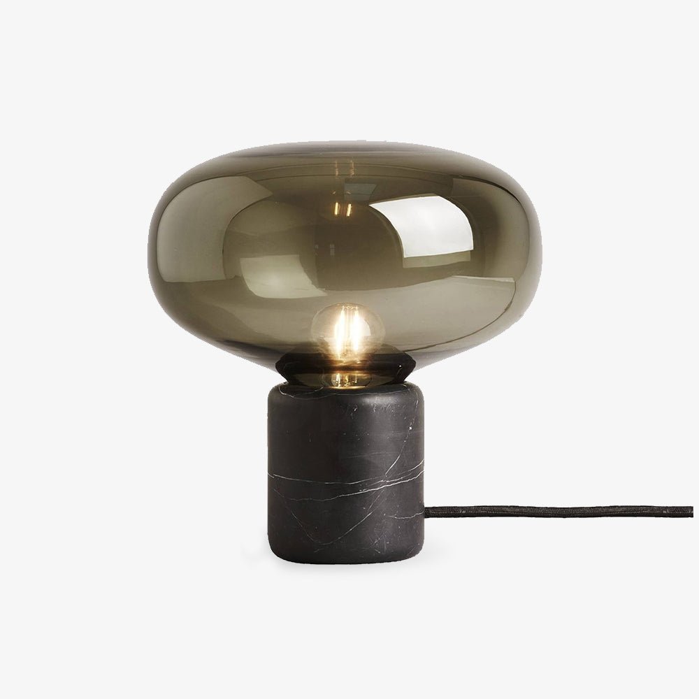 A studio shot of the Clérachic table lamp on white, its cord looped loose beneath the smoke-grey glass dome.