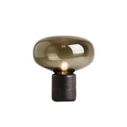A studio shot of the amber-glass Clérachic table lamp on white, showing the full silhouette from a slight angle.