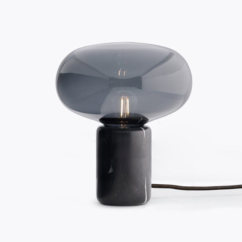 A front-facing studio shot of the Clérachic table lamp on white, its cord trailing to the right of the marble base.