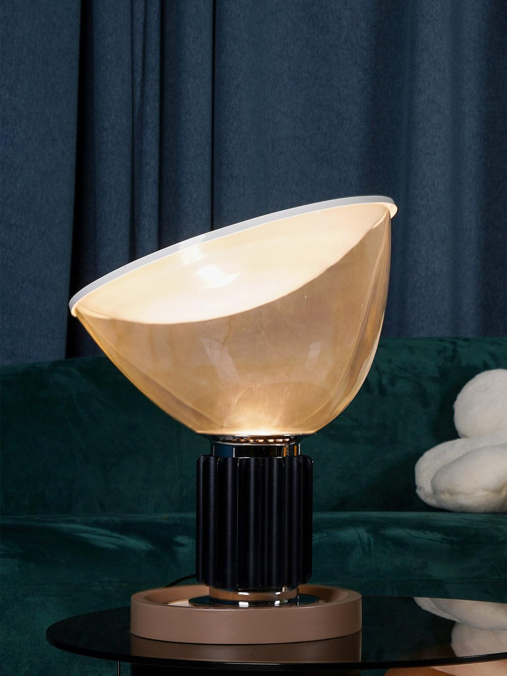 Warm-lit table lamp with white reflector on bedside table