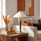 Walnut base table lamp with warm light shown against a wall
