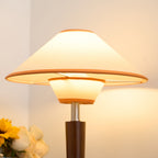Green fabric table lamp with walnut base on a wooden desk
