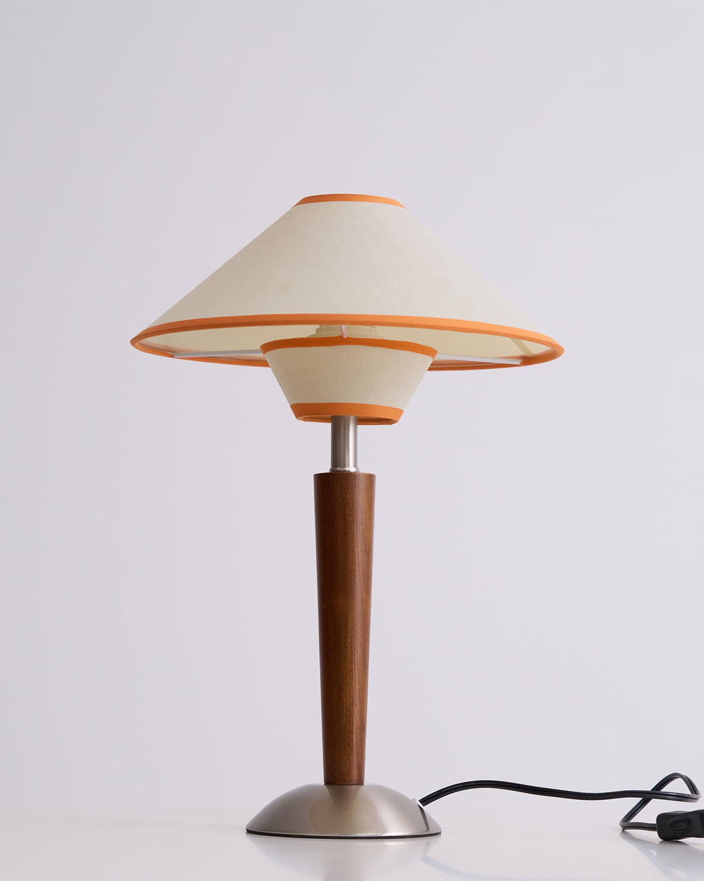 Fabric shade lamp on walnut base glowing in a styled lounge