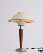 Fabric shade lamp on walnut base glowing in a styled lounge