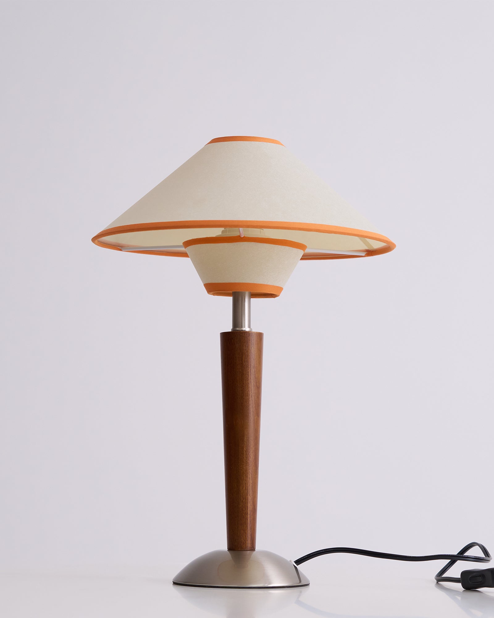 Fabric shade lamp on walnut base glowing in a styled lounge