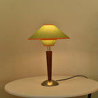Beige fabric table lamp with walnut base beside an armchair