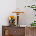 Fabric shade table lamp with walnut base in a soft lit room