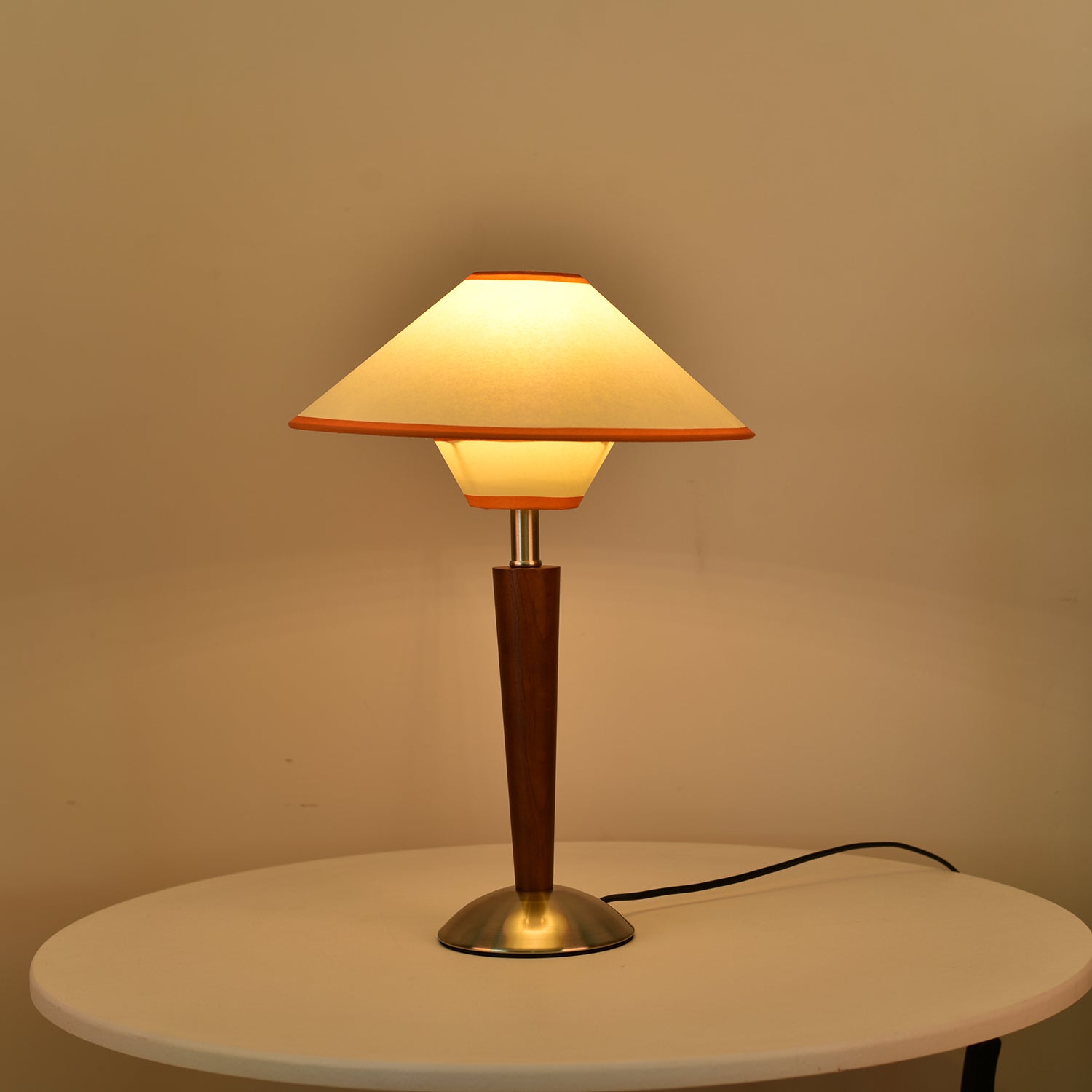 Tan fabric shade table lamp glowing warmly on a nightstand