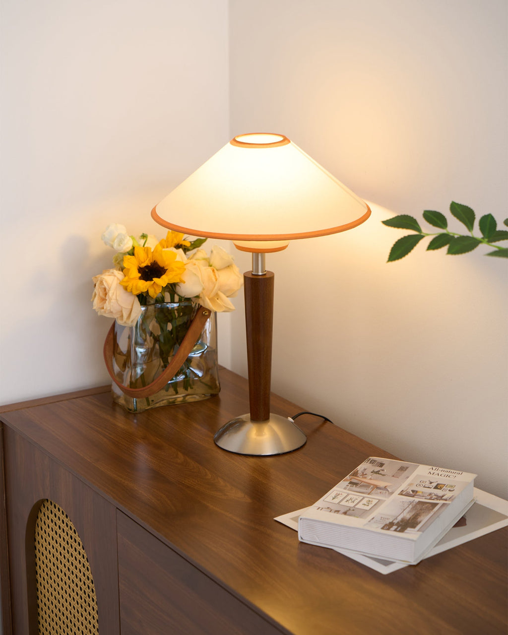 Beige fabric shade table lamp casting warm light at a bedside