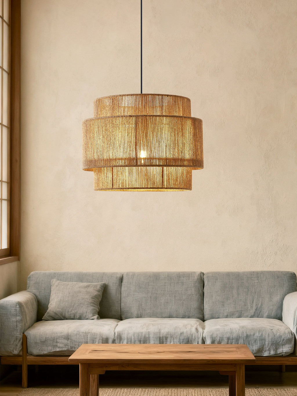Over a grey sofa and wood coffee table, this Clérachic pendant adds warmth to a plaster-walled living room.
