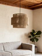 In a room with a wood-beamed ceiling and a fiddle-leaf fig, this Clérachic pendant hangs above a grey armchair corner.