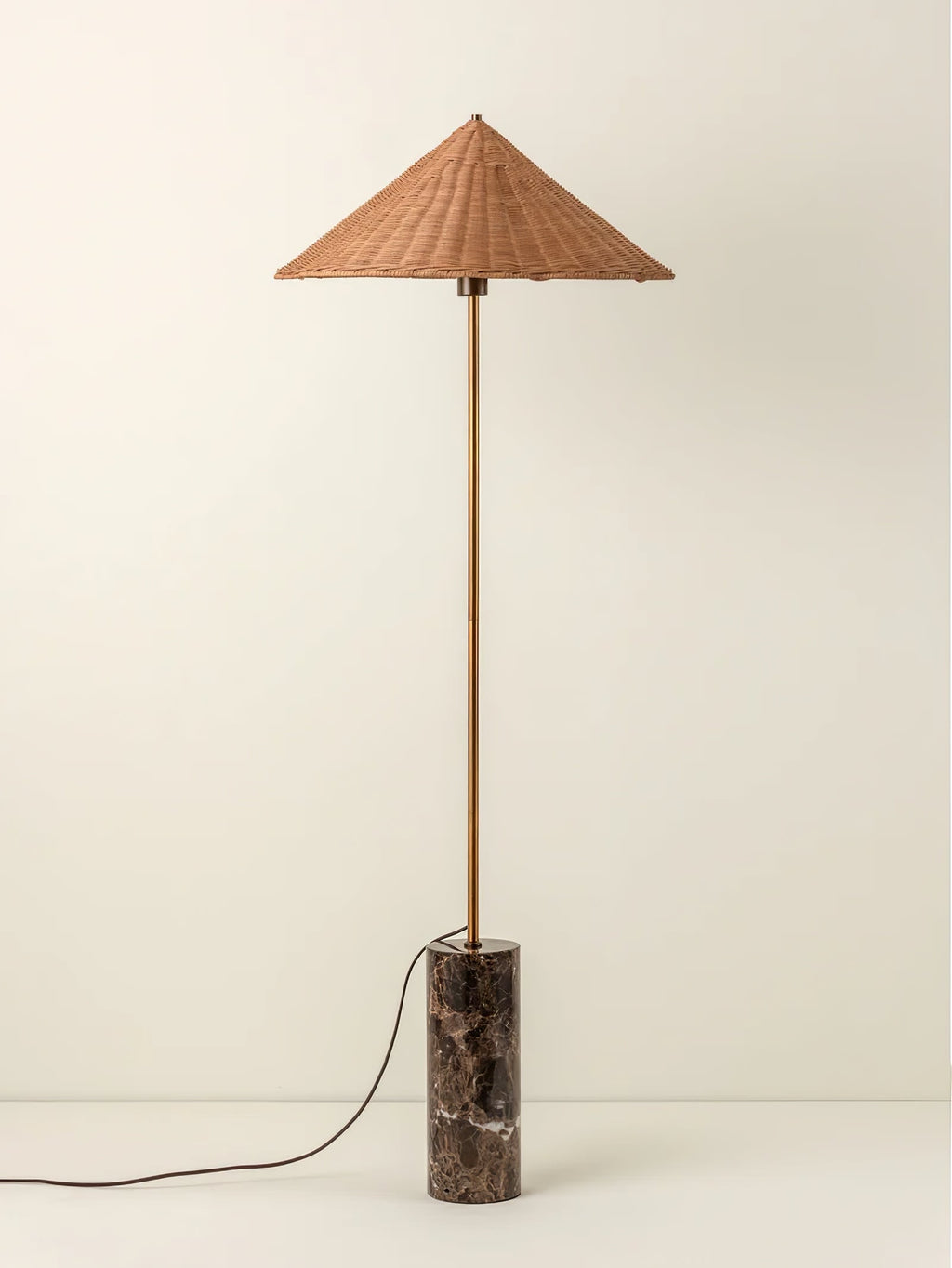 Clérachic rattan cone-shade floor lamp on its dark marble base, photographed full length against a soft cream studio backdrop.