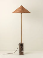 Clérachic rattan cone-shade floor lamp on its dark marble base, photographed full length against a soft cream studio backdrop.