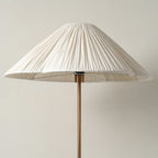 Close-up from above of the pleated white shade on a Clérachic floor lamp, showing the brass finial and stem beneath it.
