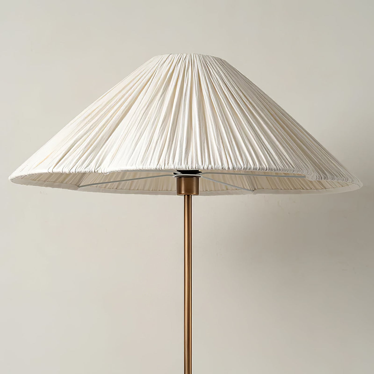 Close-up from above of the pleated white shade on a Clérachic floor lamp, showing the brass finial and stem beneath it.