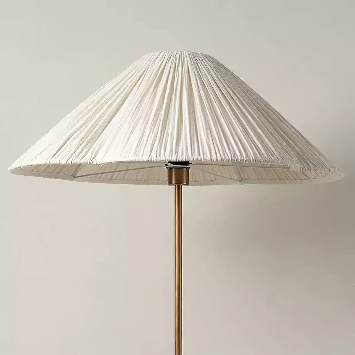 Close-up of the pleated white shade and brass stem on a Clérachic floor lamp, with its bottle-shaped base visible below.