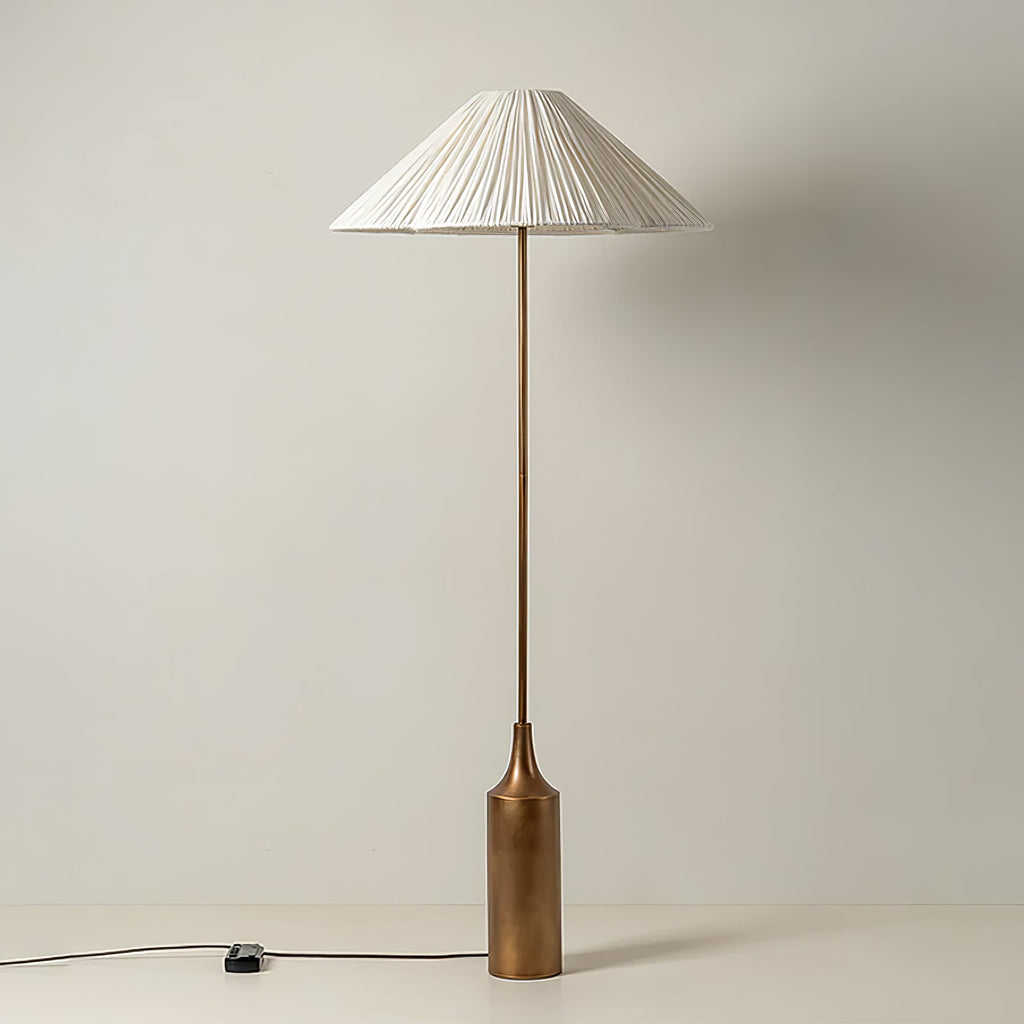 The cord and inline switch rest on the floor beside this Clérachic pleated white cone-shade floor lamp's brass bottle base.