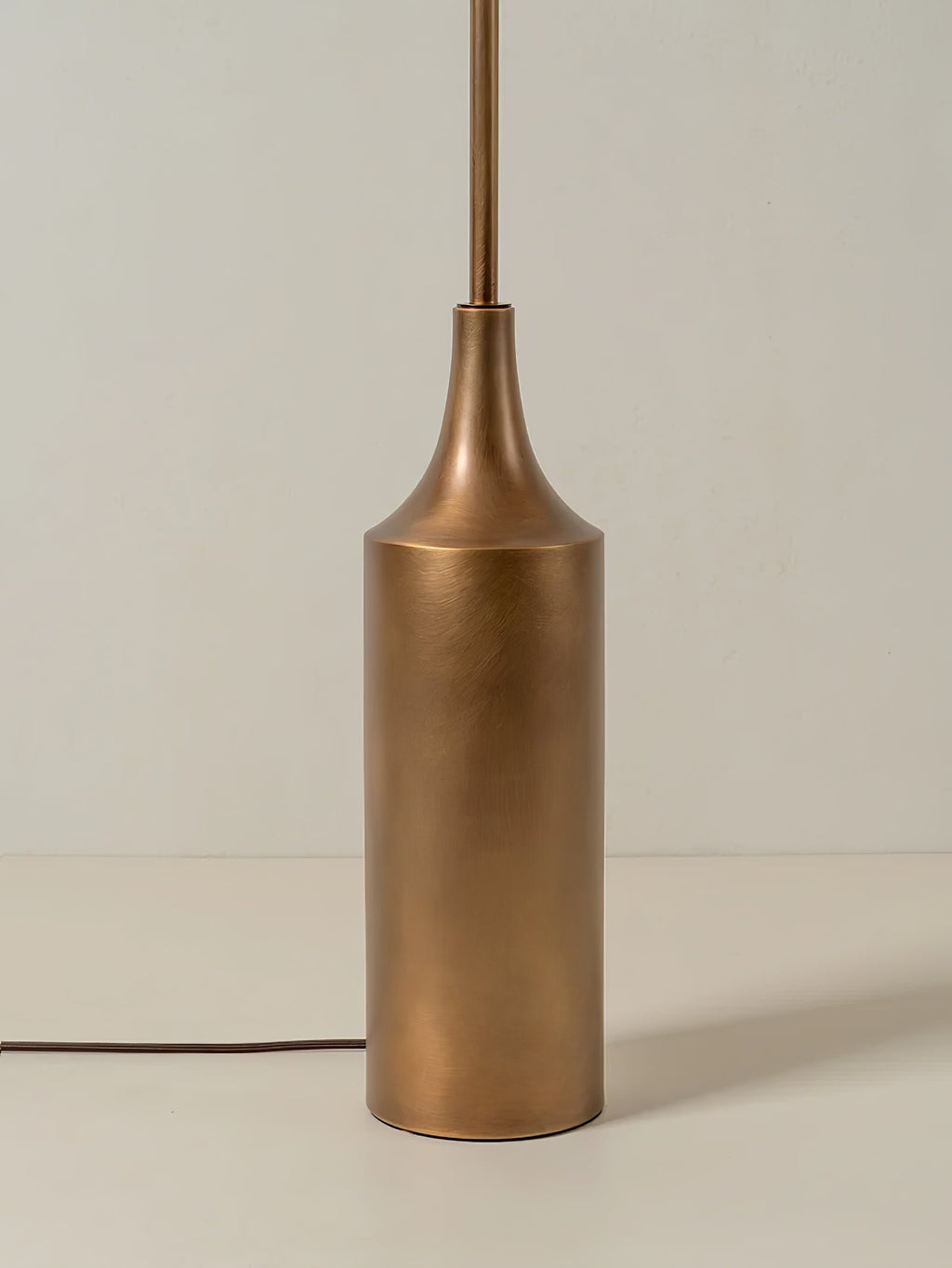 Close-up of the cylindrical brass bottle-shaped base on a Clérachic floor lamp, with its cord and inline switch visible.