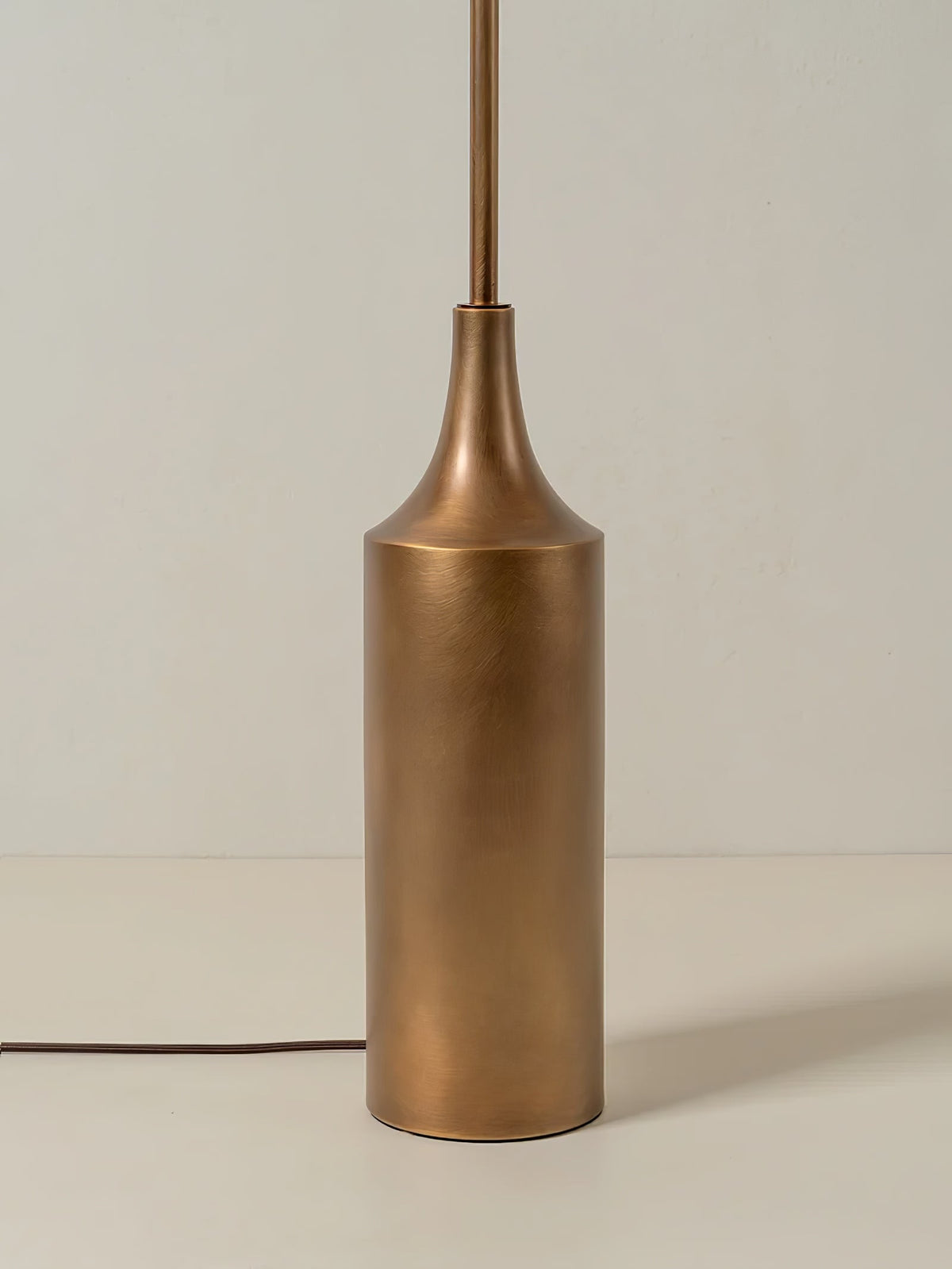 Close-up of the cylindrical brass bottle-shaped base on a Clérachic floor lamp, with its cord and inline switch visible.