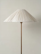 Close-up of the pleated white fabric shade on a Clérachic floor lamp, showing its fine vertical pleats and slender brass stem.