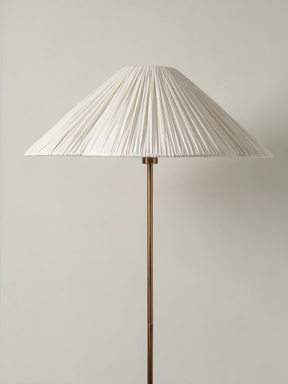 Close-up of the pleated white fabric shade on a Clérachic floor lamp, showing its fine vertical pleats and slender brass stem.