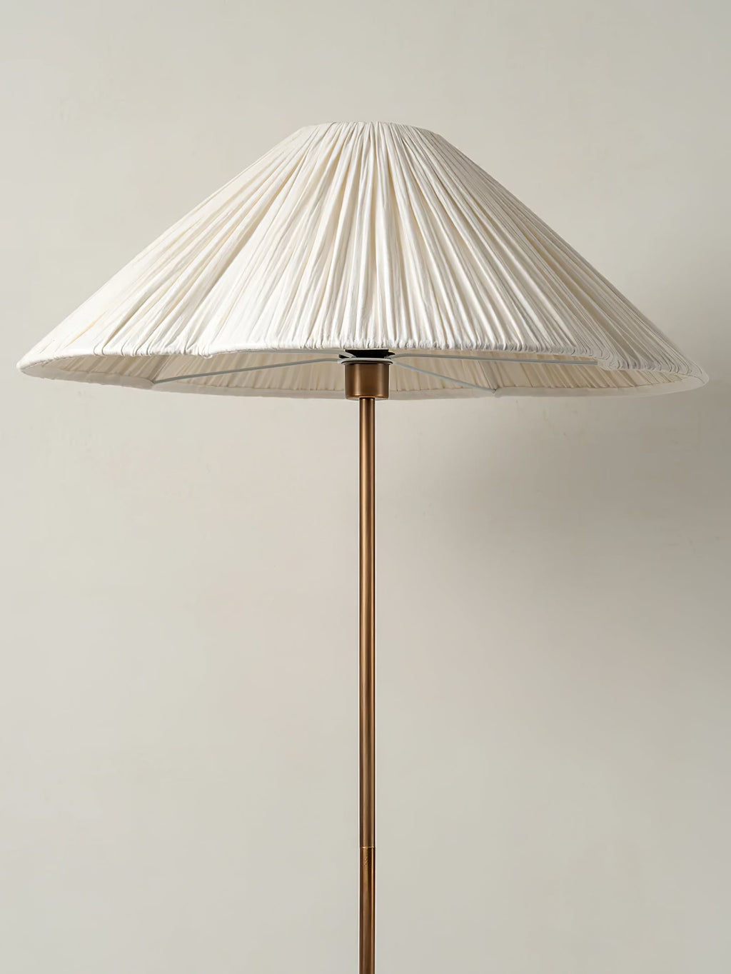 Clérachic pleated white cone-shade floor lamp shown full length on its brass stem against a plain light grey background.