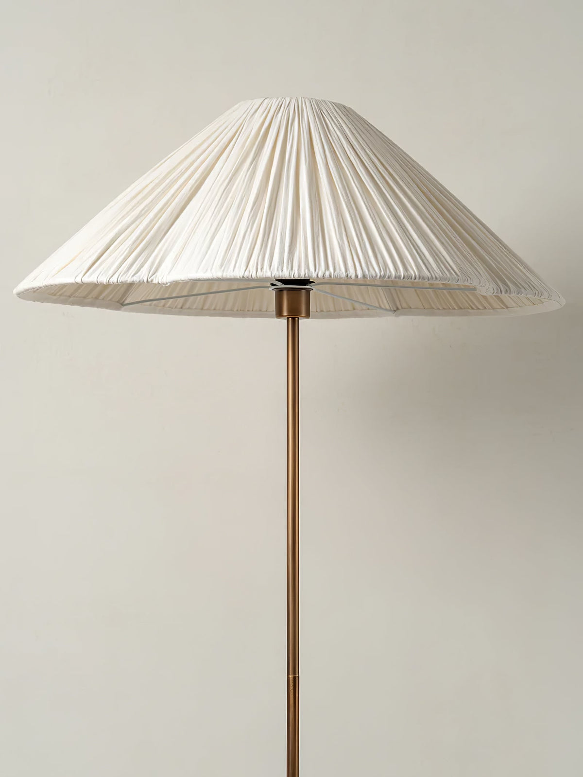 Clérachic pleated white cone-shade floor lamp shown full length on its brass stem against a plain light grey background.