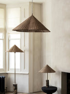 Two Clérachic rattan cone-shade pendant lights hang above a plinth and floor lamp in a bay window with panelled walls.