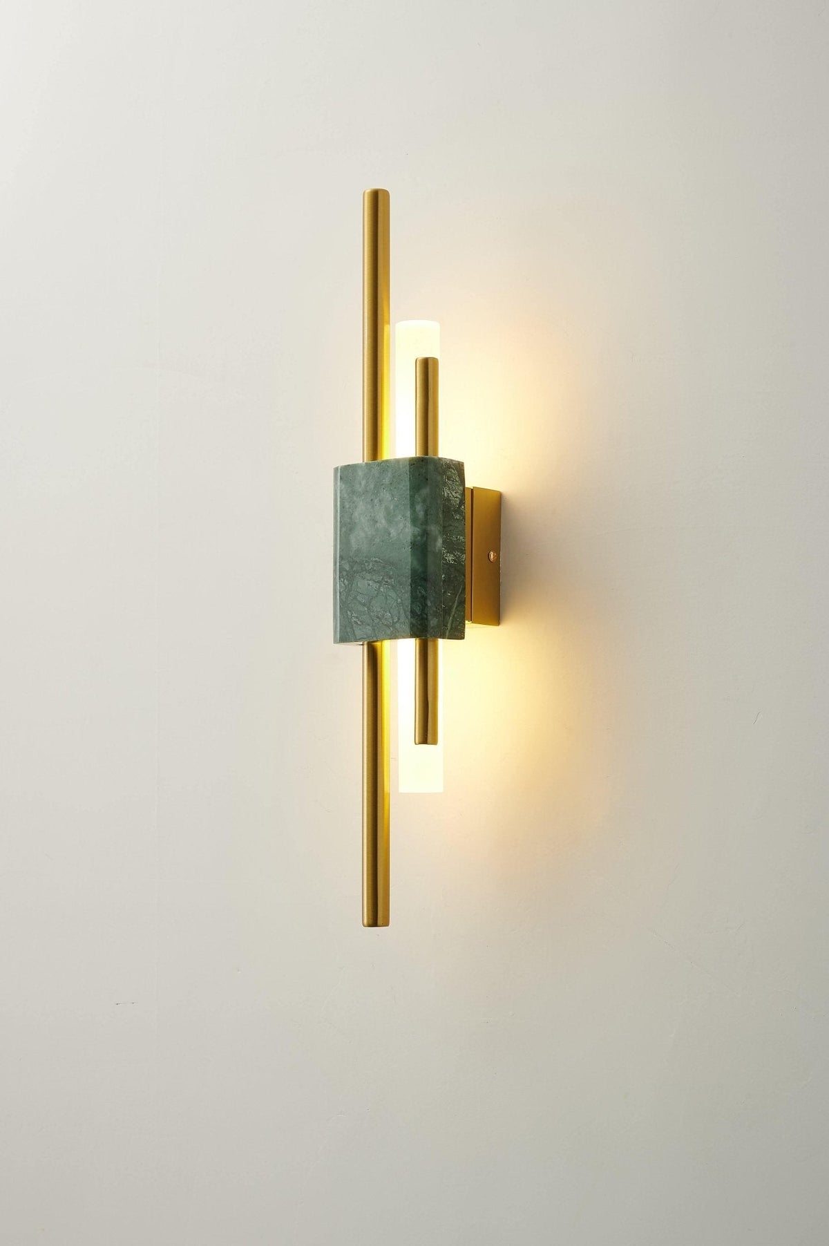 Clérachic wall light with green marble front, lit, on a plain cream wall in a straightforward product view.