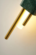 Another angled close-up shows this Clérachic wall sconce's green marble front and brass rods lit against white.