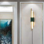 Clérachic brass-rod wall light with a white marble block hangs in a hallway lined with a blue abstract painting and a skylight.