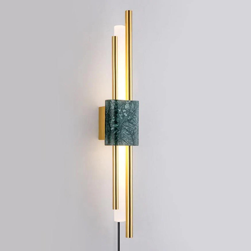 A green marble block sits between glowing brass rods on this Clérachic wall sconce, photographed straight-on against a grey wall.