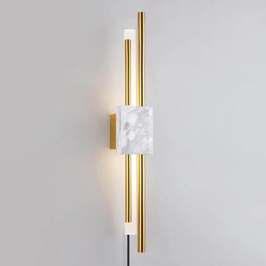 A white marble block sits between glowing brass rods on this Clérachic wall sconce, photographed straight-on against a plain grey wall.