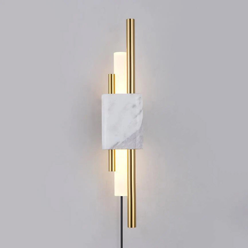 With its plug-in cord visible below, this Clérachic wall sconce's brass rods and frosted glass tubes glow against a grey wall.