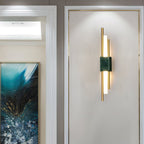 Marble and gold sconce throwing warm light up the wall