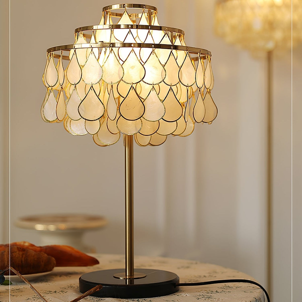Clérachic table lamp glowing on a round table, croissants and blueberries arranged close to its black marble base.