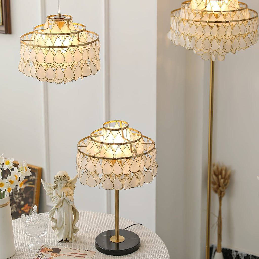 Clérachic table lamp lit beside a small porcelain angel figurine and a vase of daffodils, a pendant shade soft-focus above.