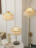 Clérachic table, floor and pendant lamps glowing together in a room with a small porcelain angel and a gift box.
