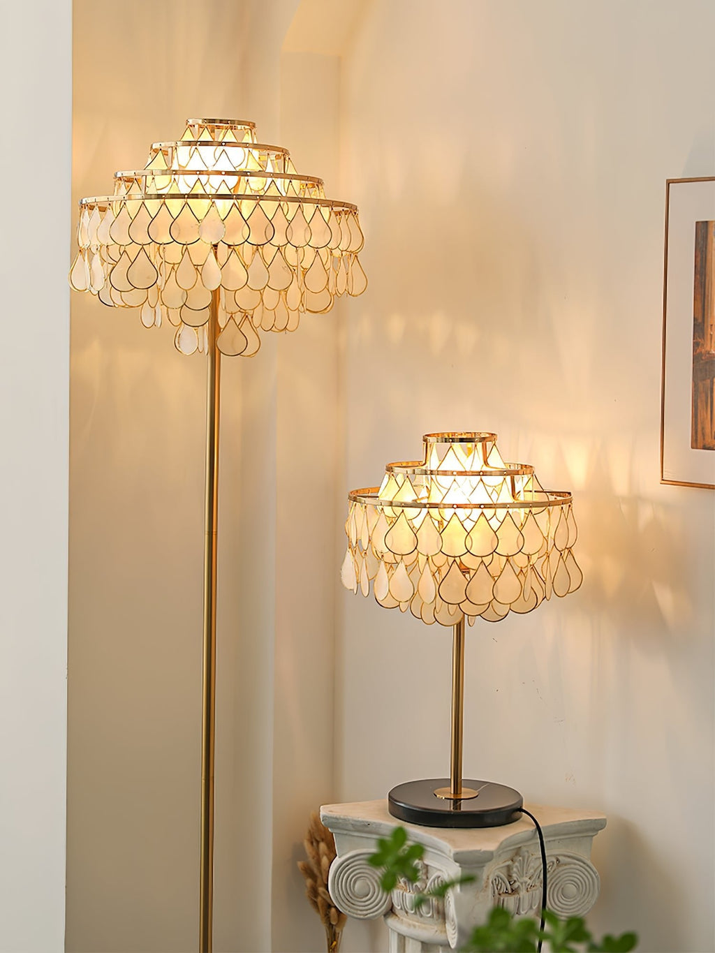 Clérachic table lamp and a taller floor lamp glowing in a warm hallway beside a small plant stand and framed art.